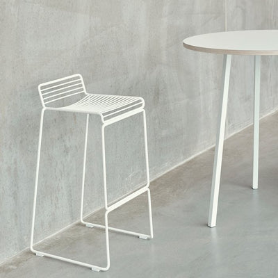 The absence of superfluous details in the Hee Bar Stool seems even more pronounced by its height and the presence of long slender legs. The ultimate in elemental design, this versatile bar/counter stool has a simple, uncluttered expression with excellent stability. Stackable and weather-proof, the Hee Bar Stool can be used in outdoor surroundings, as well as inside restaurants, bars and in the home.